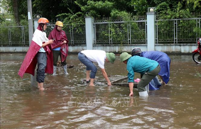 Trong ảnh: Người dân cùng lực lượng chức năng khơi thông một số điểm cống bị tắc nghẽn. Ảnh: Văn Tý-TTXVN