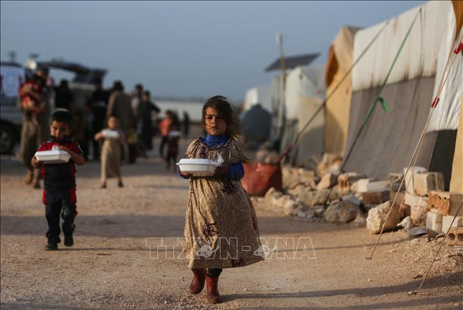 Trong ảnh: Trẻ tị nạn Syria nhận lương thực viện trợ từ một tổ chức từ thiện tại khu lều trại ở ngoại ô thị trấn Dana, phía Đông tỉnh biên giới Idlib. Ảnh: AFP/TTXVN