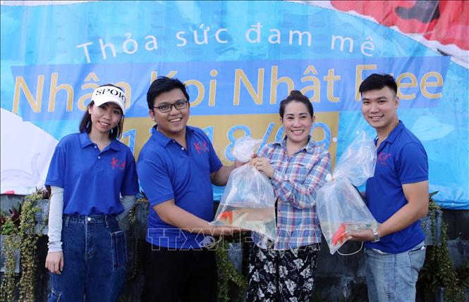 Trong ảnh: Nhân viên Koi Service trao tặng cá cho người dân nuôi trải nghiệm. Ảnh: Trần Lê Lâm – TTXVN 