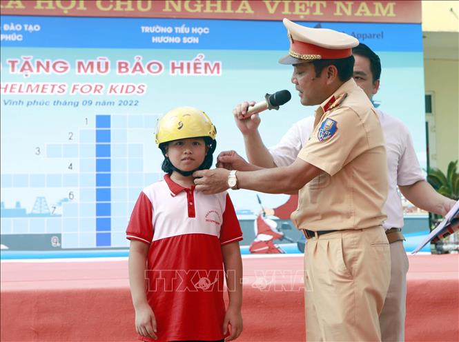 Trong ảnh: Thiếu tá Phạm Văn Hòa, công an huyện Bình Xuyên, hướng dẫn học sinh đội mũ bảo hiểm đúng cách tại chương trình. Ảnh: Hoàng Hùng -TTXVN