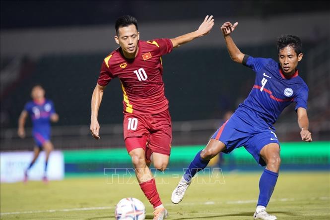 Vietnamese (red shirt) and Singaporean (blue shirt) football players fight for the ball in the match. VNA Photo: Thanh Vũ