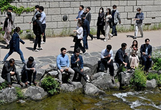 Trong ảnh: Người dân di chuyển trên đường phố tại Seoul, Hàn Quốc, ngày 2/5/2022. Ảnh: AFP/ TTXVN