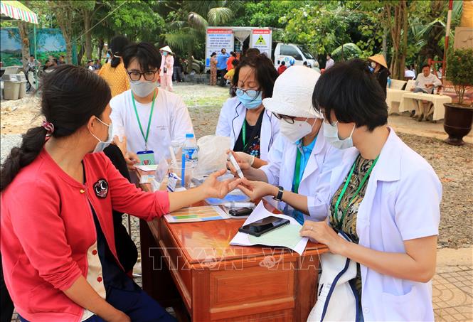 Lực lượng y tế kiểm tra đường huyết cho người dân đến khám bệnh. Ảnh: Phạm Minh Tuấn-TTXVN.