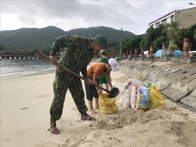 Cán bộ chiến sĩ Đồn biên phòng Cù Lao Chàm, bộ đội biên phòng Quảng Nam giúp đỡ người dân gia cố mái nhà bằng bao tải cát. Ảnh: Đoàn Hữu Trung - TTXVN