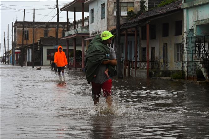 Trong ảnh: Người dân di chuyển trên một tuyến phố ngập lụt do bão Ian tại Batabano, Cuba ngày 27/9/2022. Ảnh: AFP/TTXVN
