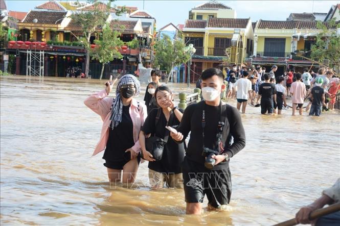 Khách du lịch vui thích khi trải nghiệm cảnh ngập lụt ở phố cổ Hội An. Ảnh: Văn Dũng - TTXVN