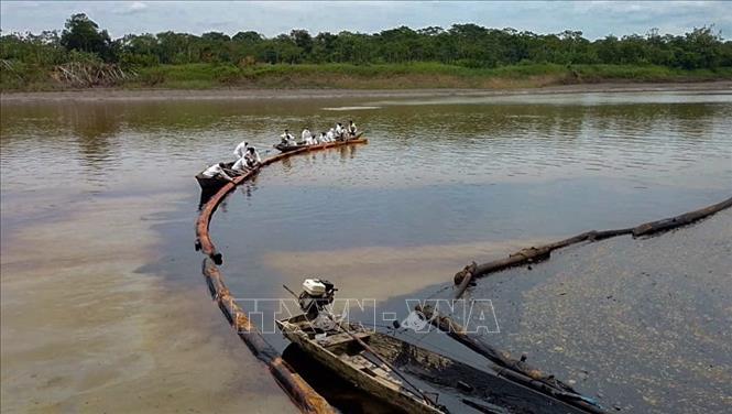 Trong ảnh: Công nhân dọn dầu loang trên sông Cuninico, một nhánh chính của sông Maranon tại Loreto, Peru ngày 18/9/2022. Ảnh: AFP/TTXVN