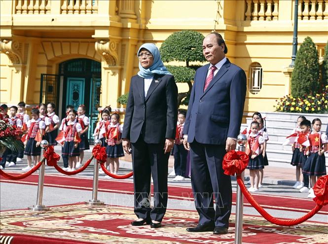 Chủ tịch nước Nguyễn Xuân Phúc và Tổng thống Cộng hòa Singapore Halimah Yacob nghe quân nhạc cử Quốc thiều hai nước. Ảnh: Thống Nhất – TTXVN