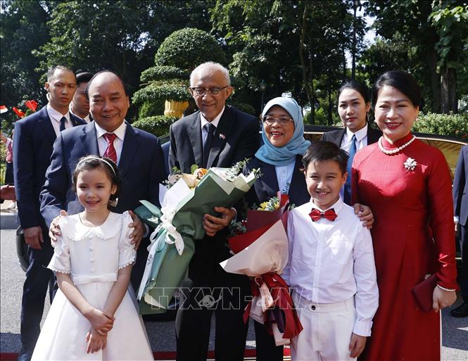 Chủ tịch nước Nguyễn Xuân Phúc và Phu nhân cùng Tổng thống Cộng hòa Singapore Halimah Yacob và Phu quân với thiếu nhi Thủ đô Hà Nội tại lễ đón. Ảnh: Thống Nhất – TTXVN
