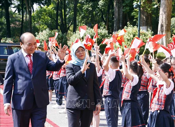Chủ tịch nước Nguyễn Xuân Phúc và Tổng thống Cộng hòa Singapore Halimah Yacob với thiếu nhi Thủ đô Hà Nội tại lễ đón. Ảnh: Thống Nhất – TTXVN