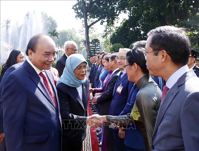 Chủ tịch nước Nguyễn Xuân Phúc giới thiệu với Tổng thống Cộng hòa Singapore Halimah Yacob các thành viên chính thức Đoàn Việt Nam tham dự lễ đón. Ảnh: Thống Nhất-TTXVN