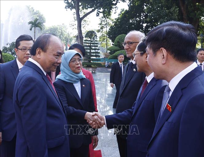 Chủ tịch nước Nguyễn Xuân Phúc giới thiệu với Tổng thống Cộng hòa Singapore Halimah Yacob các thành viên chính thức Đoàn Việt Nam tham dự lễ đón. Ảnh: Thống Nhất-TTXVN