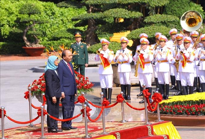 Chủ tịch nước Nguyễn Xuân Phúc và Tổng thống Cộng hòa Singapore Halimah Yacob nghe quân nhạc cử Quốc thiều hai nước. Ảnh: Văn Điệp - TTXVN