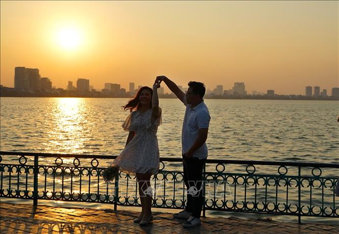 A couple enjoys their moment of autumn at twilight time at West Lake. VNA Photo: Khánh Hòa 