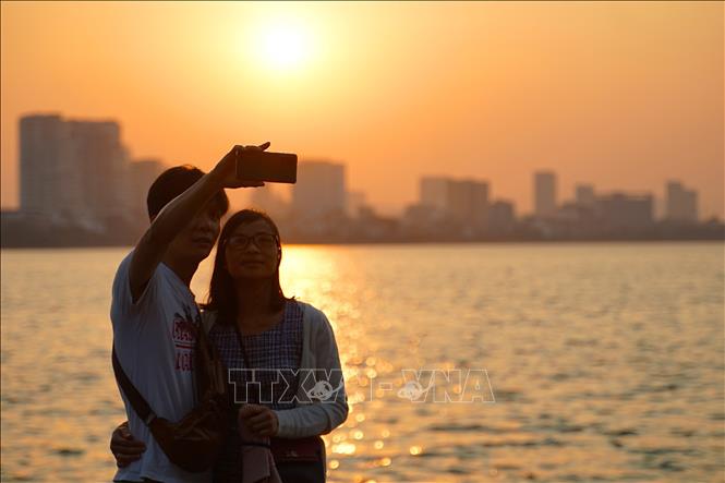 A couple enjoys their moment of autumn at twilight at West Lake. VNA Photo: Khánh Hòa 