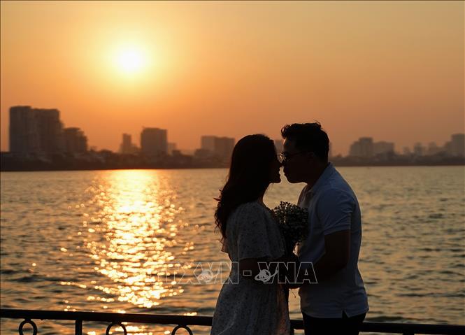 A couple enjoys their moment of autumn at twilight at West Lake. VNA Photo: Khánh Hòa 