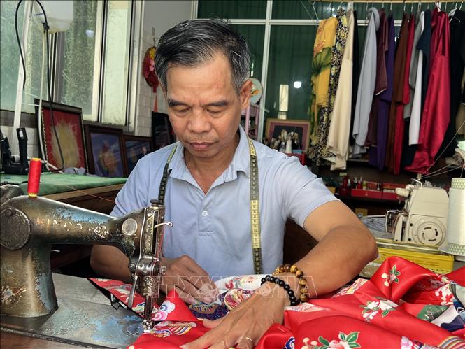 Ông Trần Thanh Tòng đang hoàn thiện chiếc áo dài cổ phục. Ảnh: Ánh Tuyết - TTXVN
