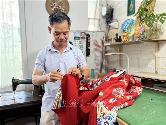 Ông Trần Thanh Tòng hoàn thiện một chiếc áo dài Nhật bình. Ảnh: Ánh Tuyết - TTXVN