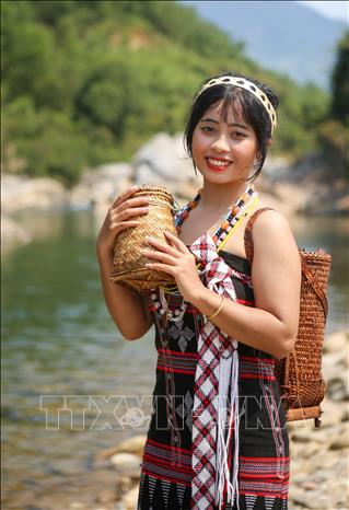 Trong ảnh: Cô gái Cơ Tu với trang phục truyền thống và các sản phẩm giỏ tre tự sản xuất. Ảnh: Trần Lê Lâm – TTXVN