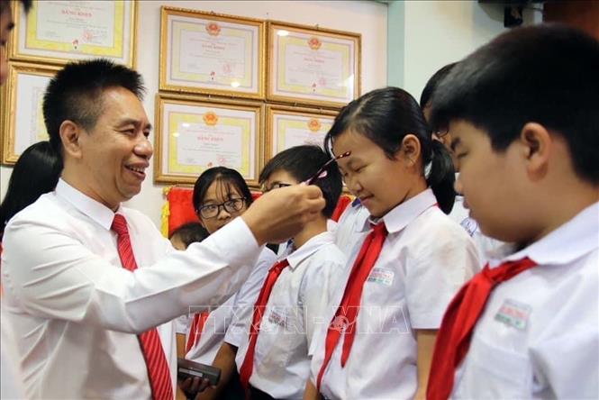 Trong ảnh: Bác sĩ Nguyễn Viết Giáp tặng kính cho các em học sinh. Ảnh: TTXVN phát 