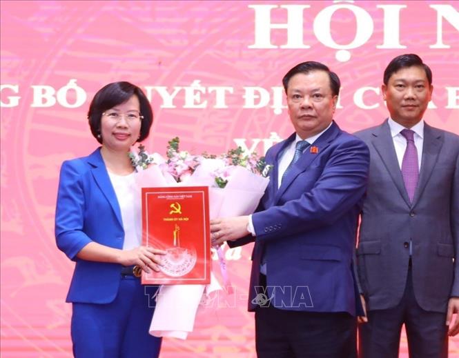 Bí thư Thành ủy Hà Nội Đinh Tiến Dũng trao quyết định, tặng hoa chúc mừng đồng chí Bùi Huyền Mai, tân Bí thư Quận ủy Thanh Xuân. Ảnh: Văn Điệp - TTXVN