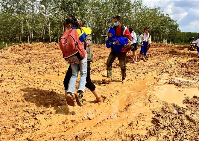 Người dân ở Trảng Rộng (xã Hải Thái, huyện Gio Linh) khổ sở lội bùn cõng con đến trường. Ảnh: Nguyên Linh-TTXVN