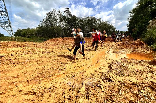 Người dân ở Trảng Rộng (xã Hải Thái, huyện Gio Linh) khổ sở lội bùn cõng con đến trường. Ảnh: Nguyên Linh-TTXVN