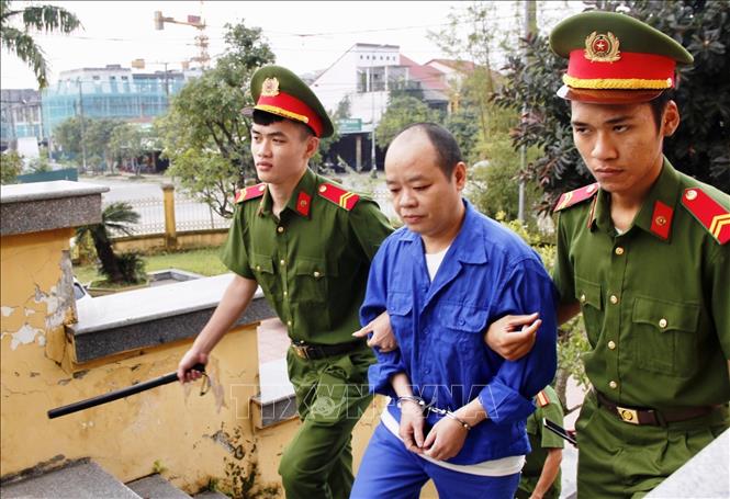 Dẫn giải cựu tu sĩ Võ Viết Đạt vào phòng xét xử. Ảnh: Nguyên Linh-TTXVN