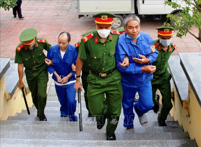 Dẫn giải cựu tu sĩ Võ Viết Đạt (bên trái) và đồng phạm Đoàn Thanh Tuấn đến tòa án. Ảnh: Nguyên Linh-TTXVN