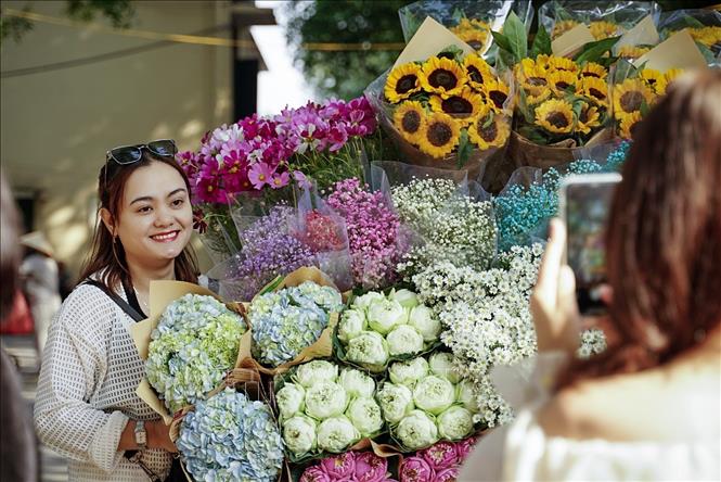 Các bạn trẻ chụp ảnh chung với xe hoa rực rỡ sắc màu. Ảnh: Khánh Hoà - TTXVN 