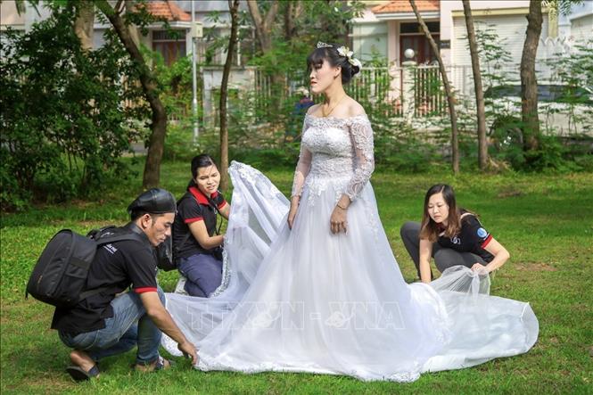 Trong ảnh: Thành viên Câu lạc bộ Chụp ảnh cưới miễn phí chuẩn bị hậu trường cho một buổi chụp. Ảnh: Hồng Giang - TTXVN.