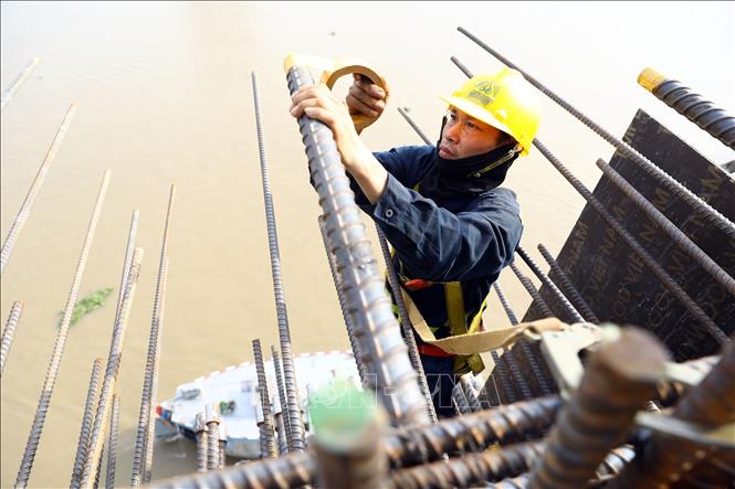 Công nhân treo mình dưới nắng nóng gay gắt để lắp đặt cốt thép tại trụ T15. Ảnh: Huy Hùng - TTXVN