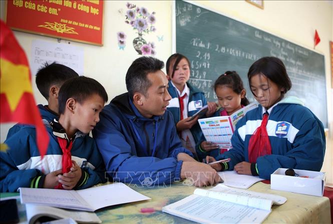 Thầy giáo Nguyễn Văn Tuân ân cần hướng dẫn học sinh làm bài tập toán trong thời gian ra chơi tại Trường PTDTBT Tiểu học và Trung học cơ sở Tung Qua Lìn. Ảnh: Quý Trung – TTXVN