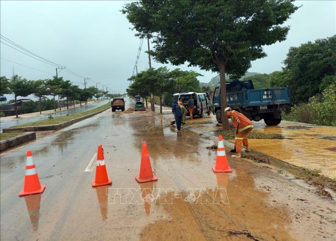 Lực lượng Công ty cầu đường 71 tập trung xử lý cát đổ xuống đường. Ảnh: TTXVN