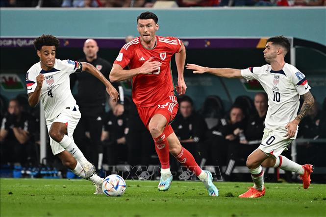 Trong ảnh: Tiền đạo Xứ Wales Kieffer Moore (giữa) đi bóng qua các tuyển thủ Mỹ. Ảnh: AFP/TTXVN