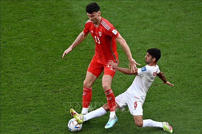 Trong ảnh: Tiền đạo  Kieffer Moore (số 13), đội tuyển Xứ Wales tranh bóng với hậu vệ Milad Mohammadi, đội tuyển Iran. Ảnh: AFP/TTXVN