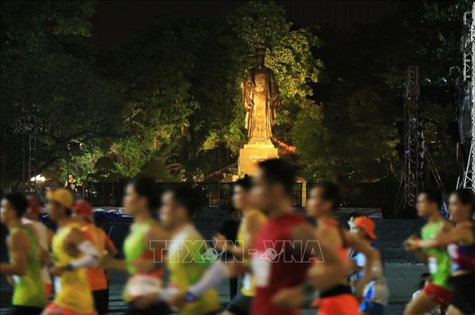 Các VĐV thi đấu ở cự ly 21 km chạy qua khu vực tượng đài Lý thái Tổ. Ảnh: Tuấn Anh - TTXVN