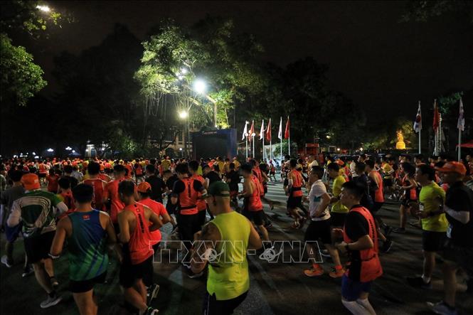 Các VĐV thi đấu ở cự ly 21 km chạy qua khu vực tượng đài Lý thái Tổ. Ảnh: Tuấn Anh - TTXVN