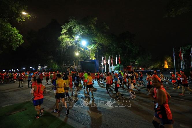 Các VĐV thi đấu ở cự ly 21 km chạy qua khu vực tượng đài Lý thái Tổ. Ảnh: Tuấn Anh - TTXVN