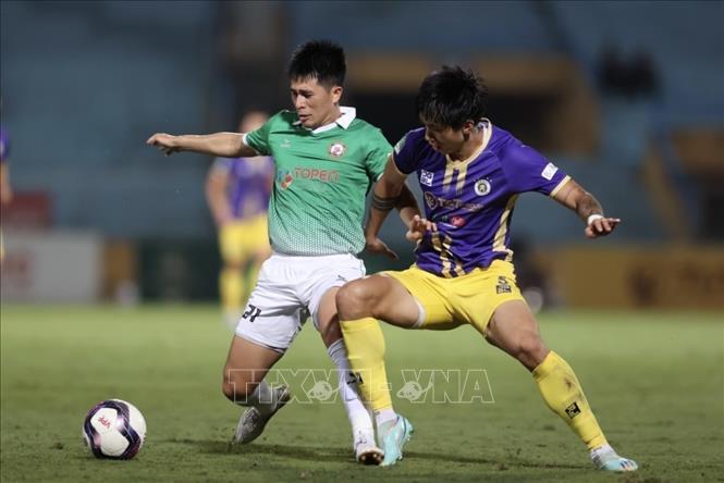 Pha tranh bóng giữa Đoàn Văn Hậu (số 5, Hà Nội) và Đình Trọng (số 21, Bình Định). Ảnh: TTXVN
