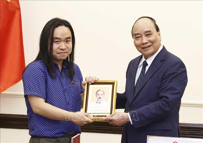 Chủ tịch nước Nguyễn Xuân Phúc tặng ảnh Chủ tịch Hồ Chí Minh cho dịch giả trẻ Nguyễn Bình. Ảnh: Thống Nhất – TTXVN
