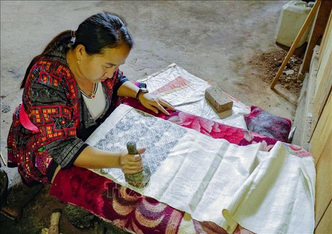 Trong ảnh: Phụ nữ Mông dùng sáp ong để tạo hoa văn lên vải. Ảnh: Xuân Tư – TTXVN