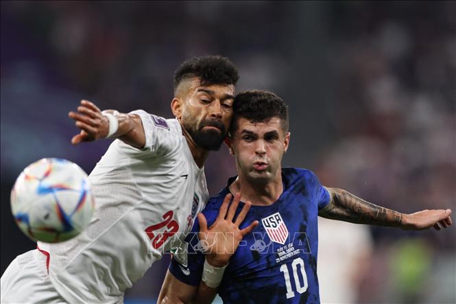 Christian Pulisic đi bóng tốc độ định xâm nhập vòng cấm của Iran, nhưng các trung vệ của đội bóng áo trắng đã truy cản kịp thời và phá bóng thành công. Trong ảnh: Pha tranh bóng quyết liệt giữa tiền đạo Mỹ Christian Pulisic (số 10) và hậu vệ Iran Ramin Rezaeian. Ảnh: AFP/ TTXVN
