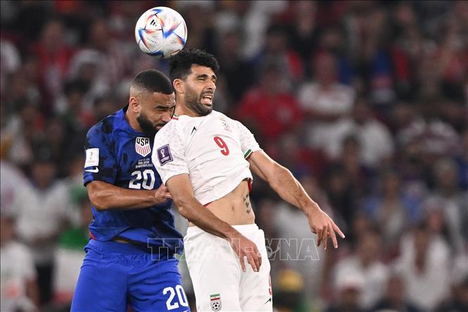 Iran phản công nhanh, Mehdi Taremi có bóng trong vòng cấm địa của Mỹ, nhưng đường chuyền sau đó của cầu thủ này cho Sardar Azmoun quá nhẹ nên bị hậu vệ đối phương hóa giải thành công. Trong ảnh: Pha tranh bóng bổng giữa tiền đạo Iran Mehdi Taremi (số 9) và hậu vệ Mỹ Cameron Carter-Vickers. Ảnh: AFP/ TTXVN