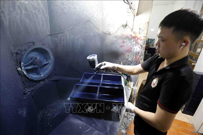 Công đoạn phun sơn trên sản phẩm khay đựng đồ tại Công ty TNHH Sơn mài Thái Sơn, làng nghề Hạ Thái. Ảnh: Trần Việt - TTXVN