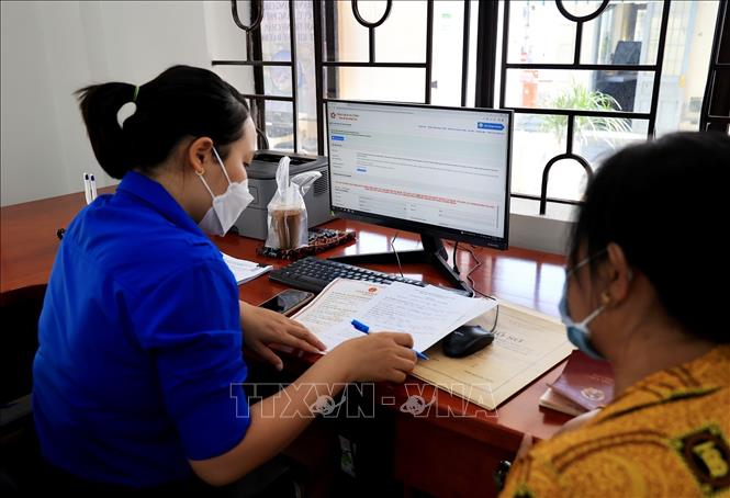 Trong ảnh: Cán bộ Đoàn thanh niên hỗ trợ người dân đăng ký tài khoản dịch vụ công, nộp hồ sơ trực tuyến. Ảnh: Hồng Đạt - TTXVN

