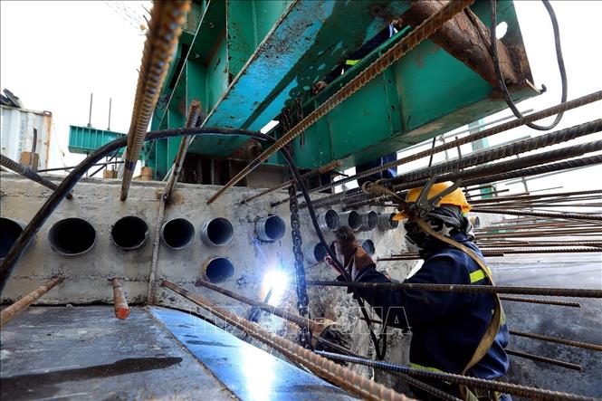 Trong ảnh: Công nhân hàn giữ treo khuôn trên trụ cầu 21. Ảnh: Tuấn Anh - TTXVN