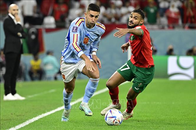 Tiền đạo Tây Ban Nha Ferran Torres (trái) đi bóng xộc thẳng vào vòng cấm không vượt qua được rừng cầu thủ bên phía Morocco. Ảnh: AFP/ TTXVN