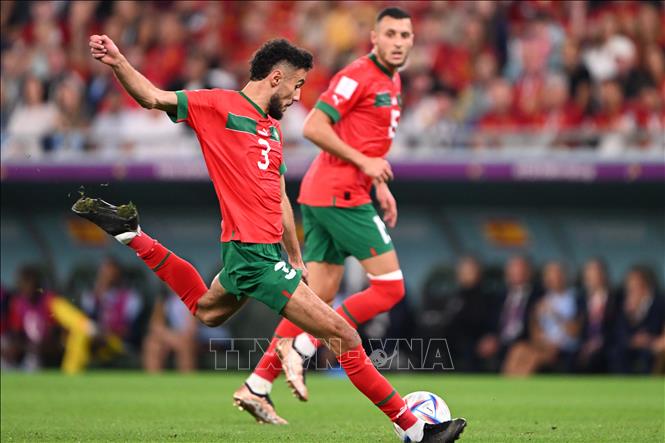 Hậu vệ Maroc Noussair Mazraoui (trái) tung ra cú dứt điểm chân trái quyết đoán từ ngoài vòng cấm nhưng bóng đi đúng vị trí thủ môn Tây Ban Nha Unai Simon đã chọn sẵn. Ảnh: AFP/ TTXVN