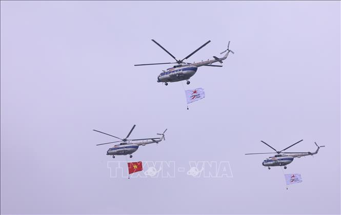 Biên đội trực thăng dòng Mi thuộc Trung đoàn không quân 916 cùng cờ Tổ quốc và cờ hiệu Triển lãm Quân sự quốc tế Việt Nam 2022 biểu diễn trên không gian triển lãm. Ảnh: Văn Điệp - TTXVN